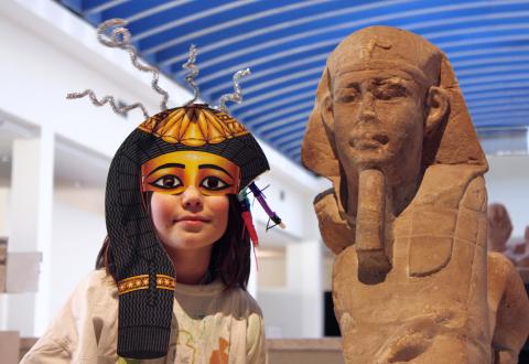 enfant avec masque égyptien à côté d'une statue de sphinx égyptien