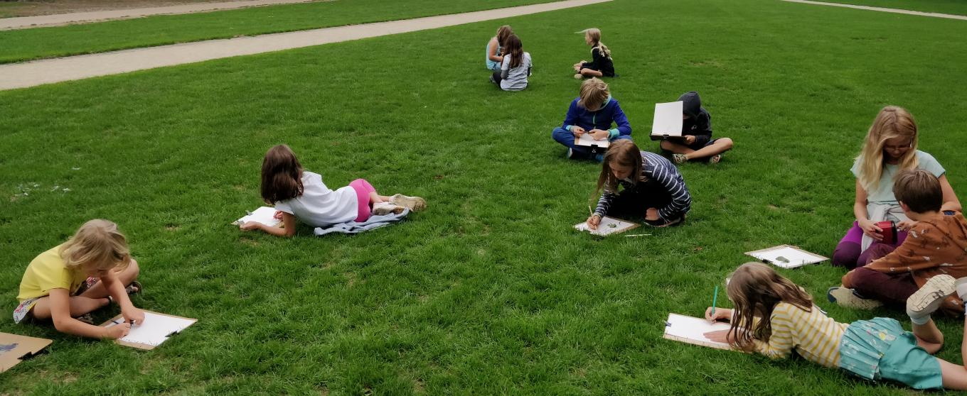 kinderen tekenen in het gras voor de triomfboog