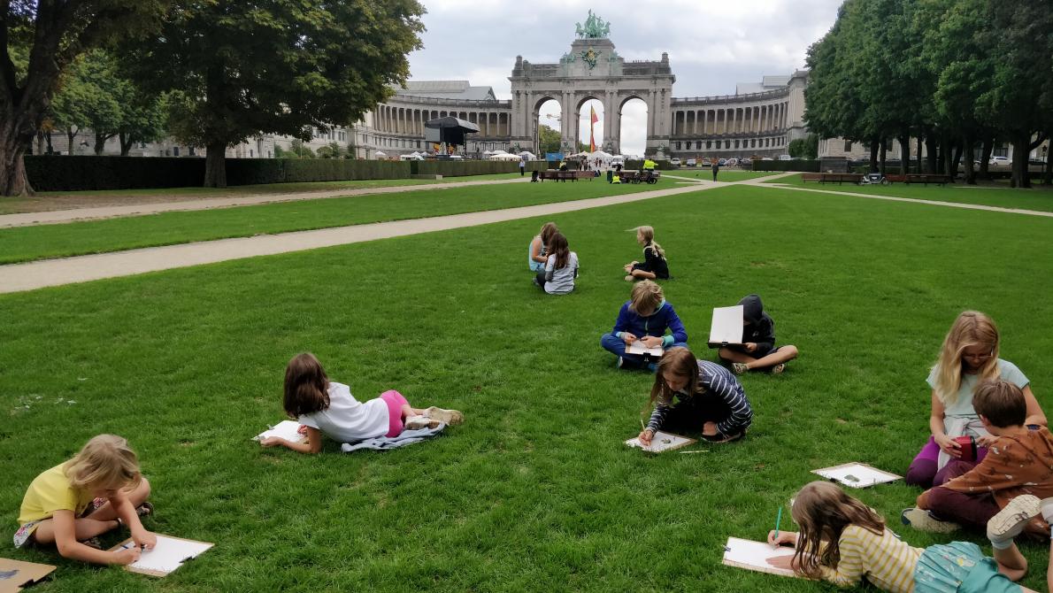 kinderen tekenen in het gras voor de triomfboog